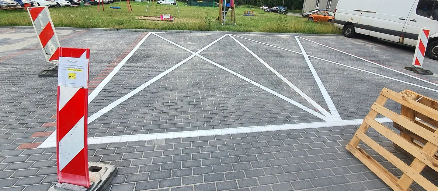Białe linie powierzchni wyłączonej z ruchu wymalowane na parkingu osiedlowym