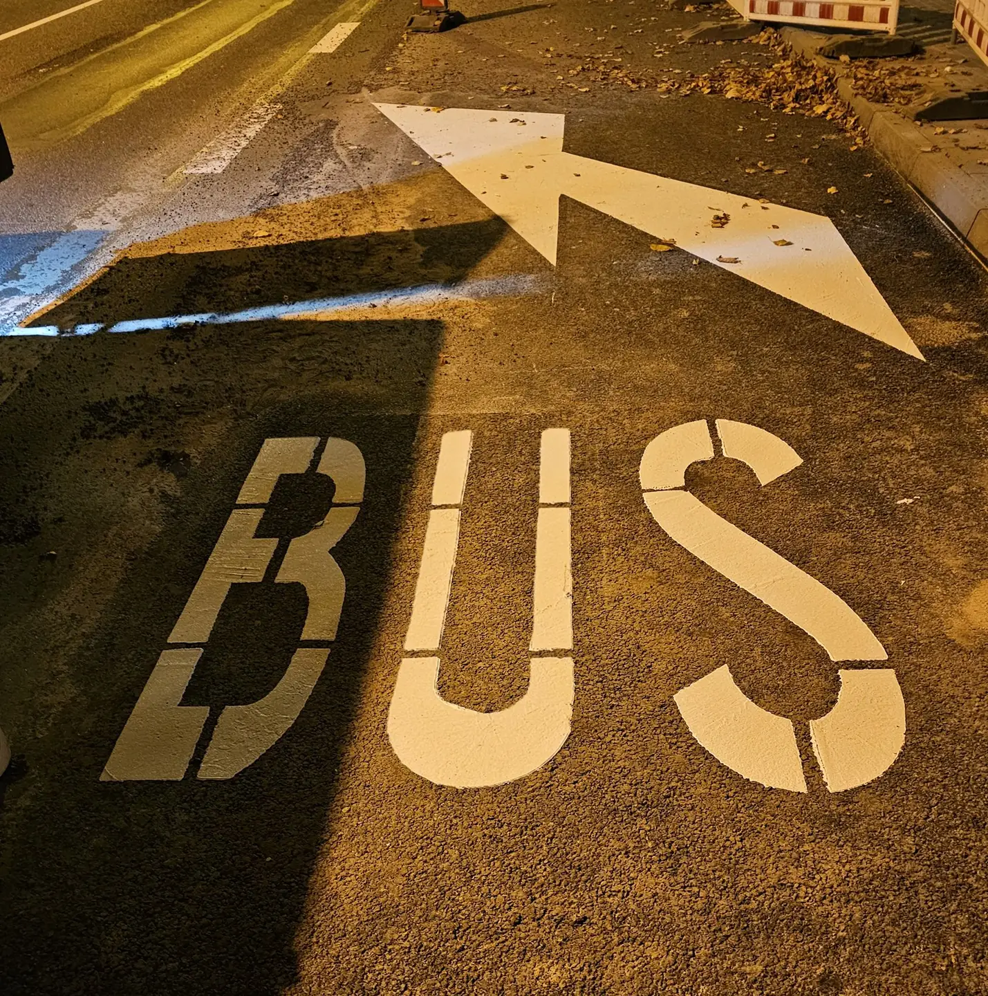 Nocne malowanie buspasa – biała strzałka i napis BUS na asfalcie